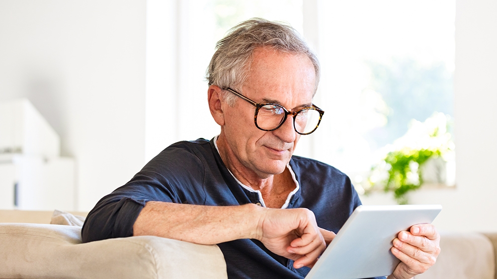 A man with glasses reads on his tablet
