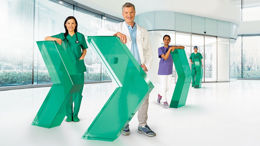 Different healthcare professionals stand behind an arrow