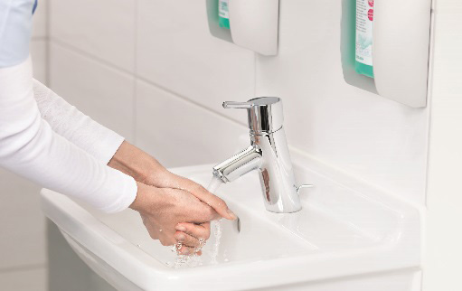 female hands under a jet of water at the bathroom sink
