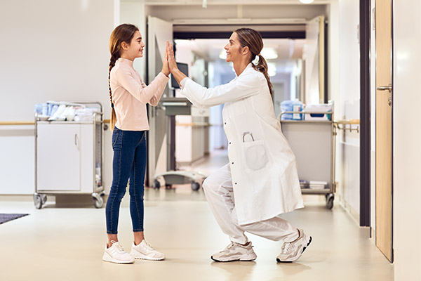 Pediatrician and patient girl high-five in the hallway
