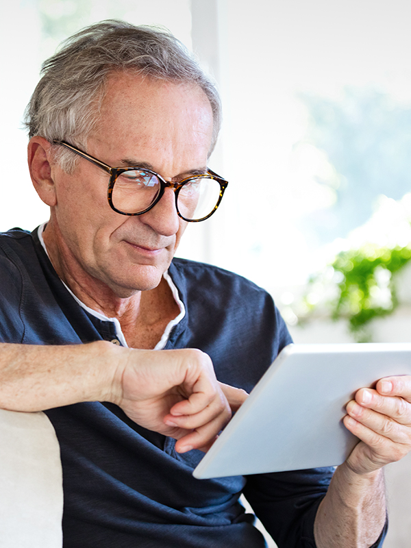 Man with glasses looks on a tablet in his hands