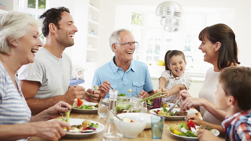 A family sits at the table eating and laughing