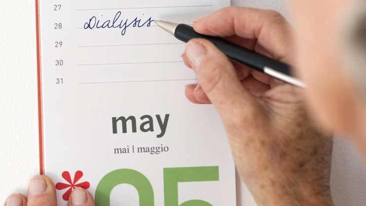 A hand writes dialysis in a calendar for 28 may with a ballpoint pen