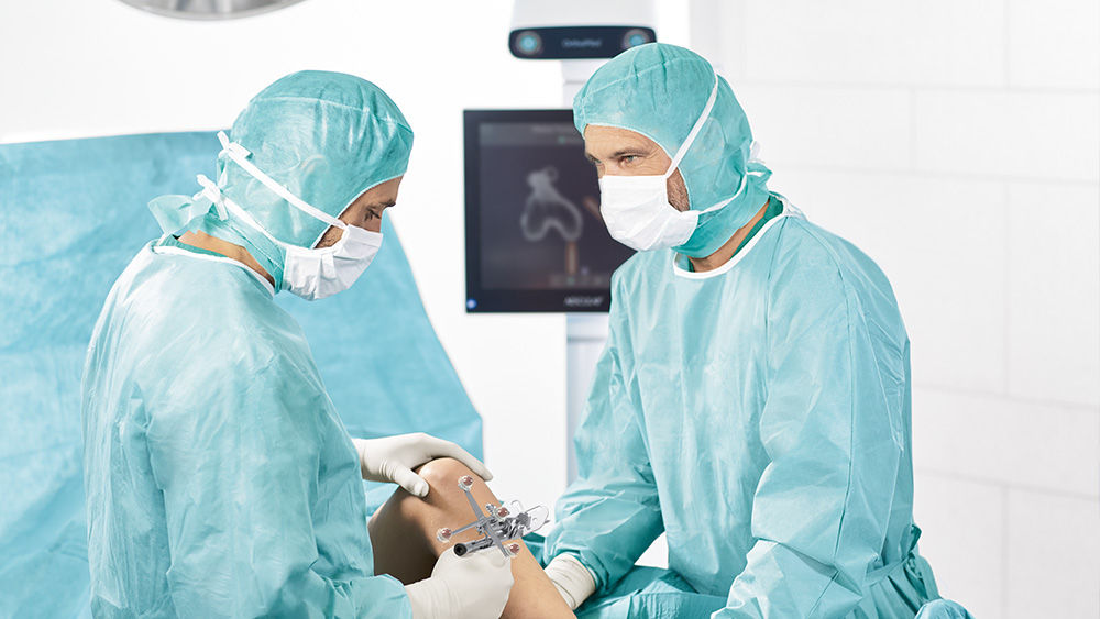Two surgeons with the OrthoPilot® Elite Multitool and monitor in the background