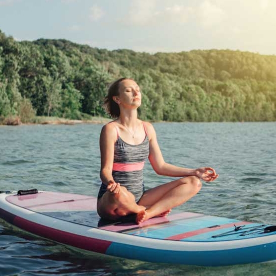 young woman who meditates on a stand-up paddle board