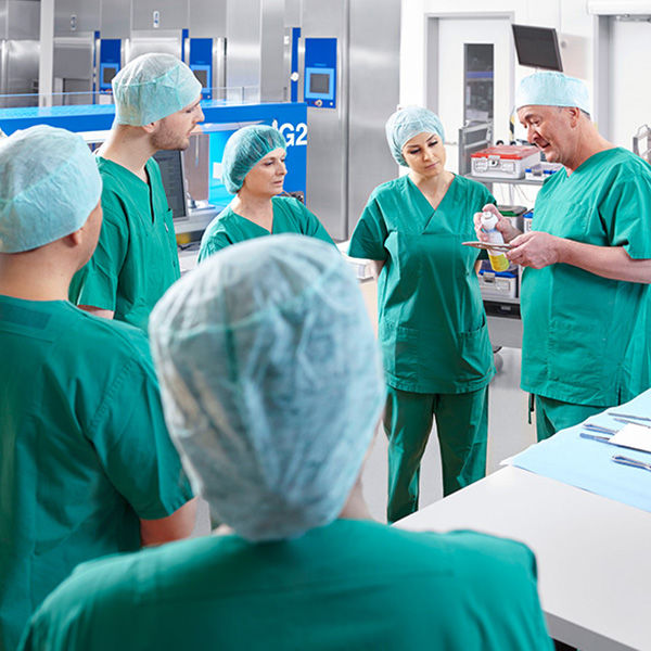 A doctor shows something to several doctors and surgical nurses in an operating room