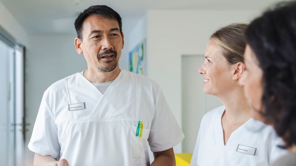 Doctor in discussion with patient and HCP standing in a reception hall.