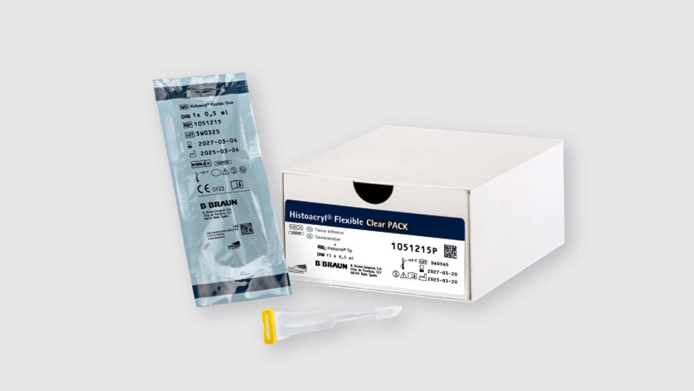 Product image showing a B. Braun Histacryl Flexible Clear Pack. A white box with a blue label sits on a neutral background, next to a sealed sterile pouch containing a vial labeled ‘DWM 1k 0.5 ml’ and a clear applicator with a yellow cap placed in front.