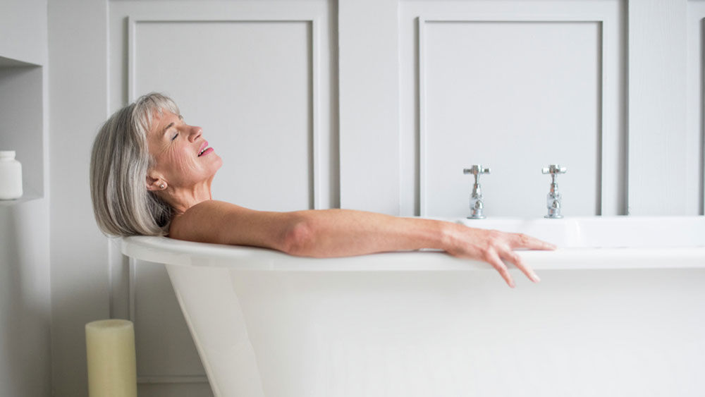 A middle-aged woman is lying in the bath