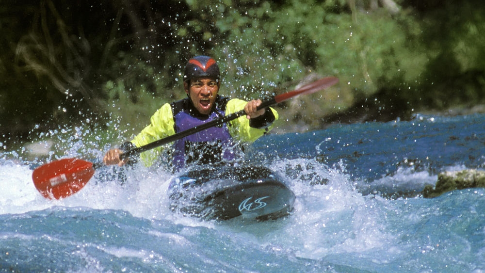 A man rides fast in a canoe with a paddle on a river