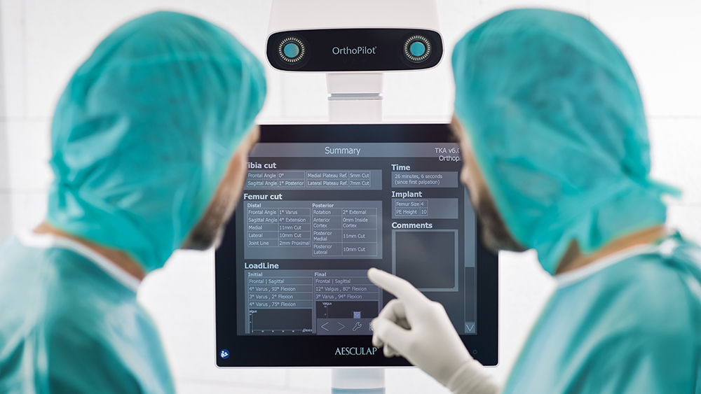 Two surgeons in front of the OrthoPilot® Elite monitor