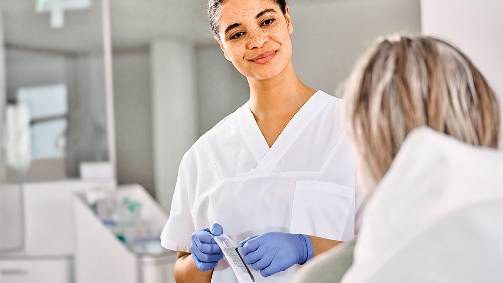 ialysis nurse opening Diacan Flex, a flexible plastic catheter, and msiling to a dialysis patient.