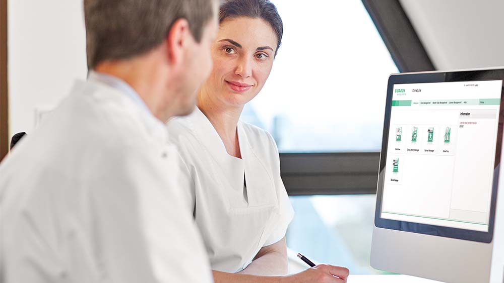 Two healthcare professionals discussing information displayed on a clinical software dashboard