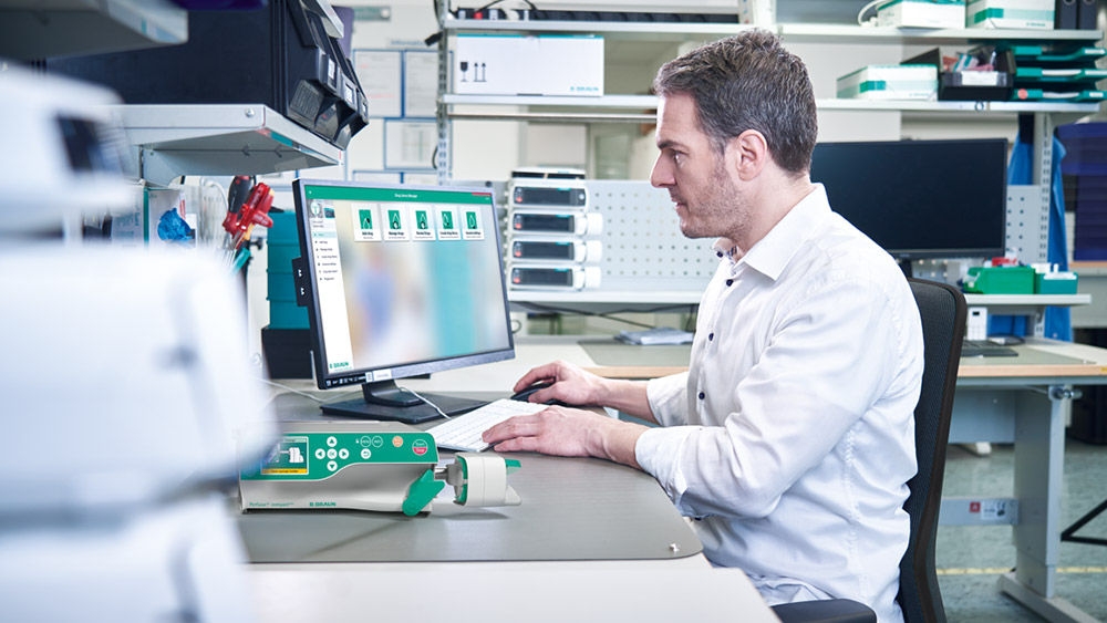 Biomedical equipment specialist managing medical device data at a laboratory workstation