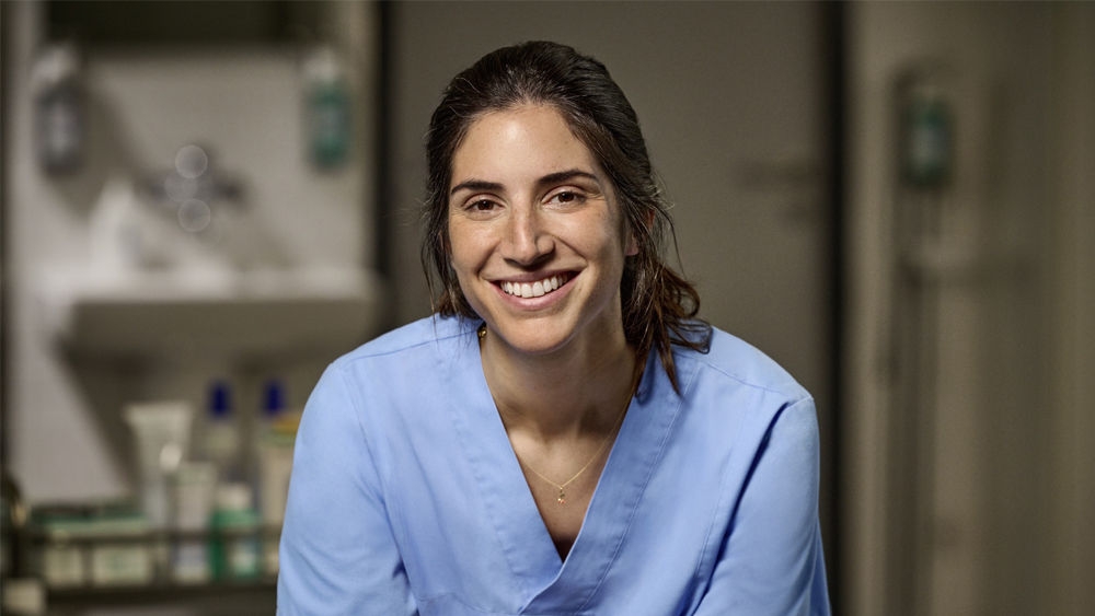 Healthcare professional wearing blue medical scrubs in a clinical setting.
