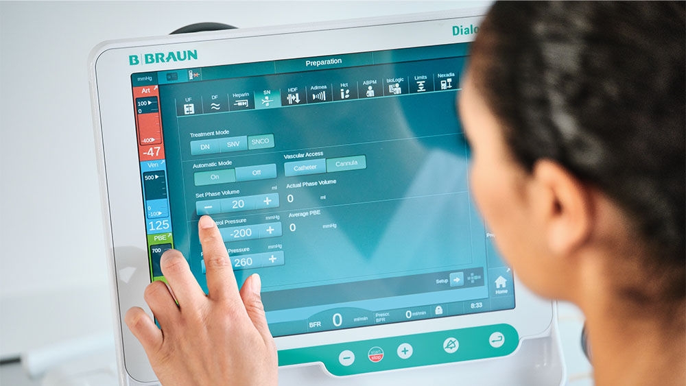 Dialysis nurse Healthcare operating dialysis machine Dialog iQ with SNCO therpay via a touchscreen.