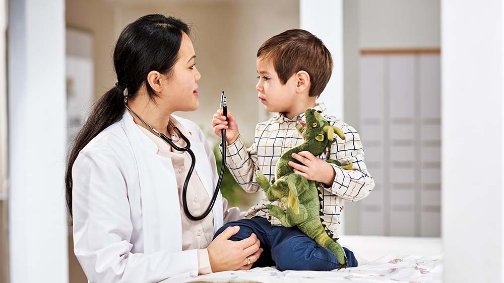 Pediatrician talking to a child holding a dinosaur