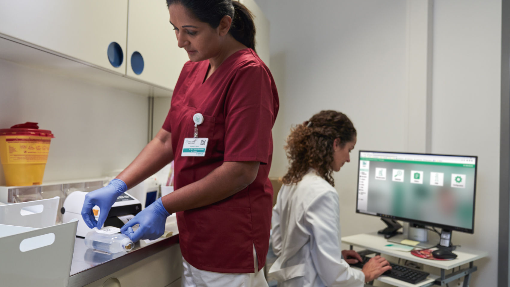 Oncology nurse preparing and labeling cytostatica for safe application and pharmacist documenting in software onco safety remote control