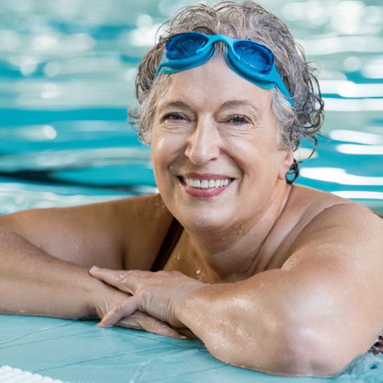 woman in swimming pool wearing swim googles on her forehead