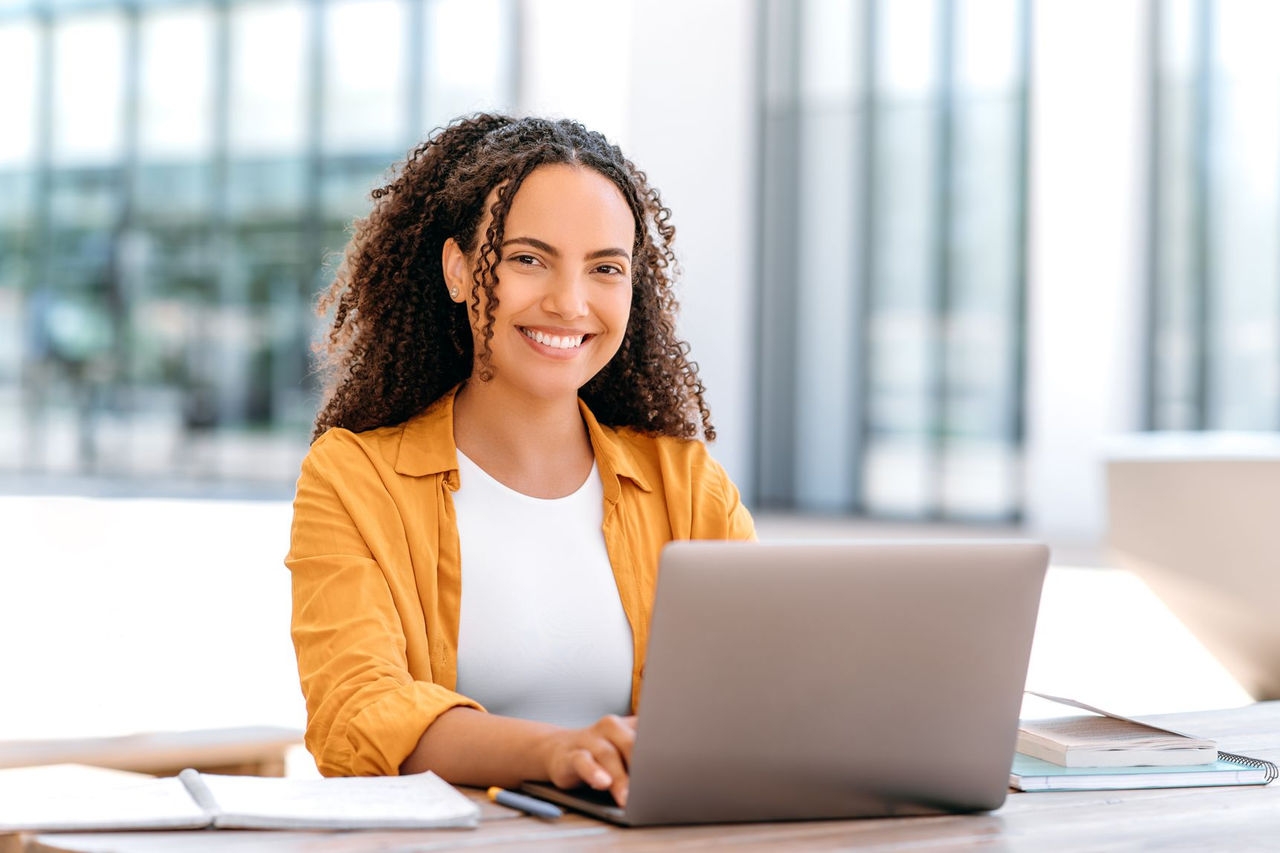 Woman with curly hair working on a laptop at a desk
