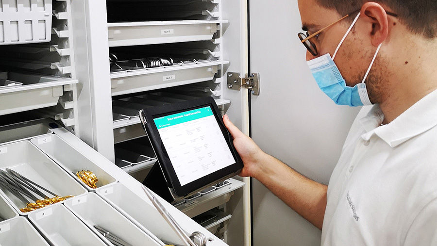 Alex Fernandez in front of a surgical instruments trolley with the BSM app on his tablet