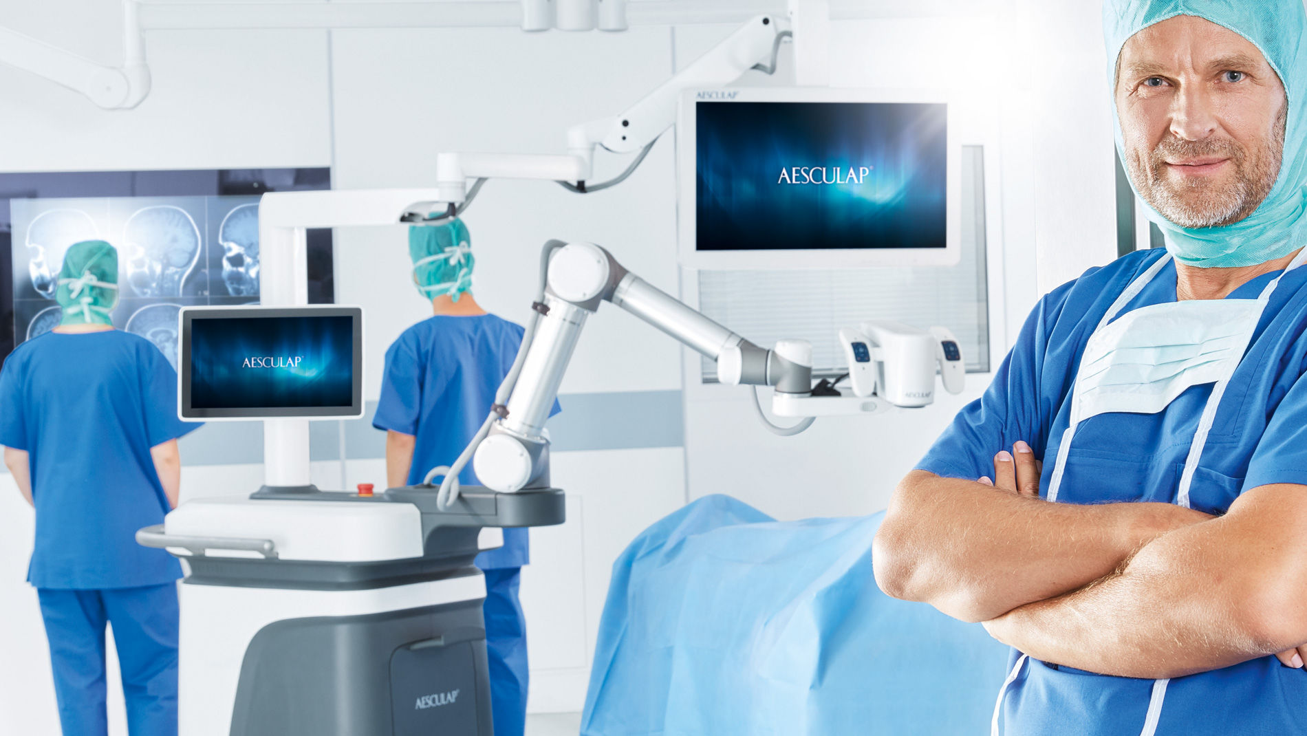 A healthcare professional standing and smiling; in the background, a room fully equipped with new medical technology, where two other medical workers are analyzing patient records.
