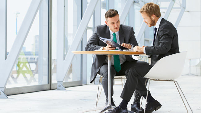 Two young man sitting at a table and talking about Aesculap Aeos®