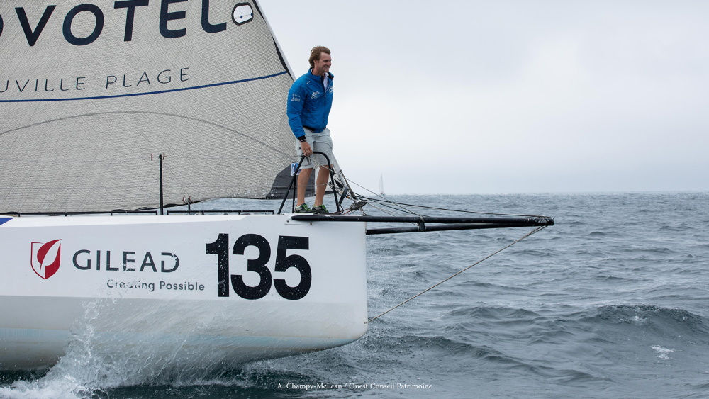 A man is standing on the edge of a moving yacht
