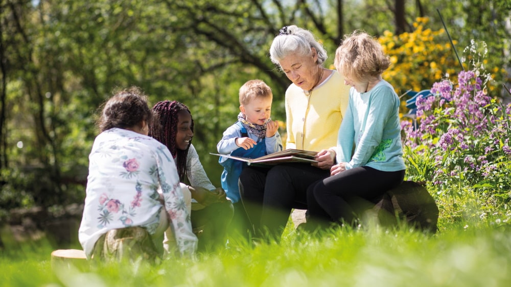 elderly woman reads to children from a book