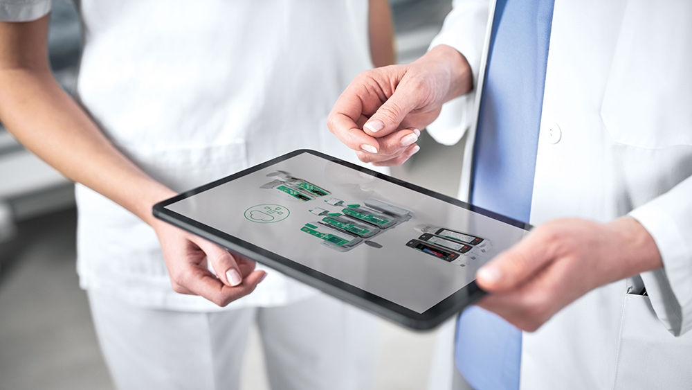  Two healthcare professionals using a tablet to review medical technology information.