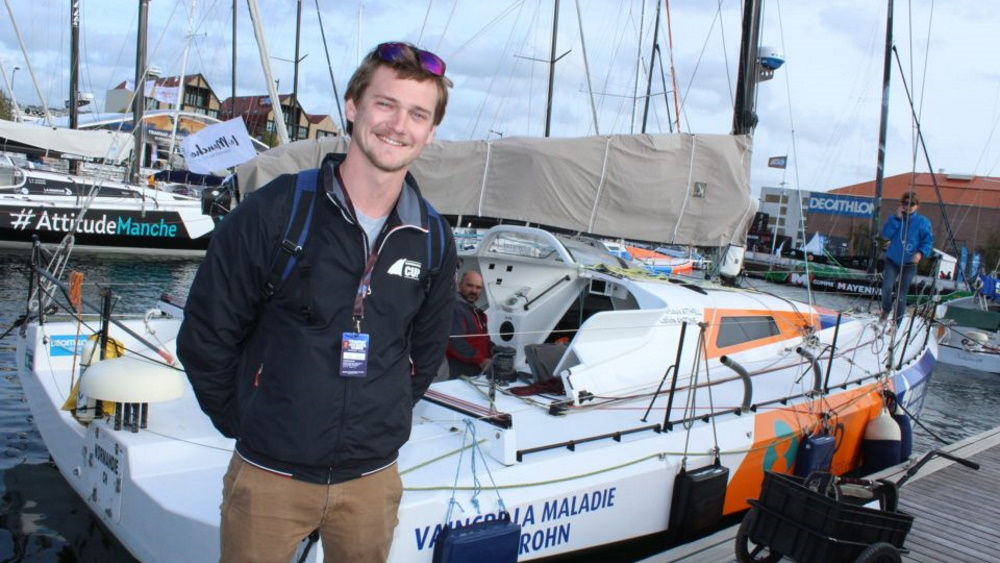 A smiling man is standing in the port in front of a yacht