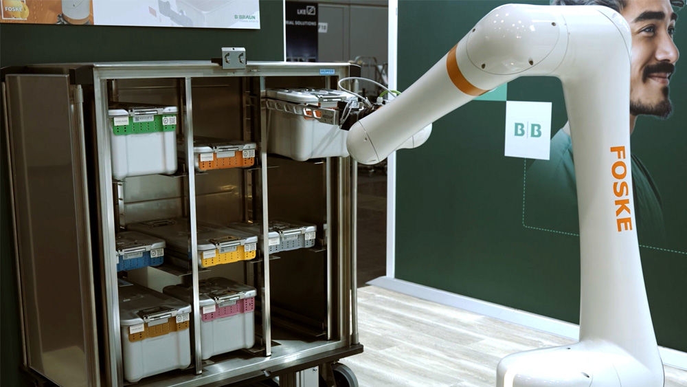 Robotic arm placing sterilization containers into a stainless‑steel storage cabinet at a medical equipment display.