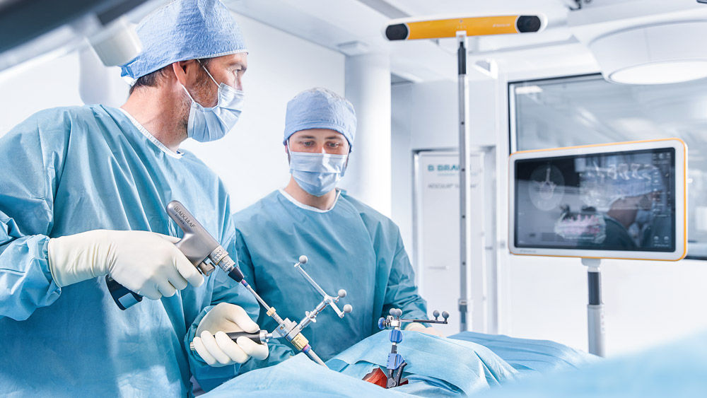 Two surgeons in the OR using a spinal navigation equipment during a surgical procedure