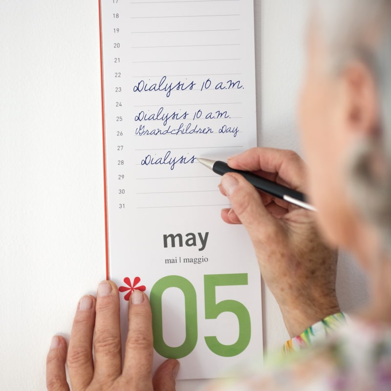 elderly woman takes notes in her calendar