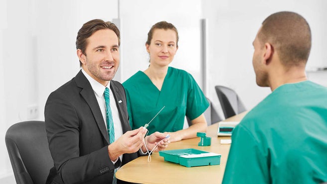Clinicians and a person in business attire reviewing a standardized ProSet pack at a table
