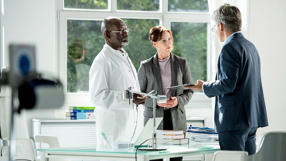 Three health care professionals meeting in a medical office and reviewing information together.