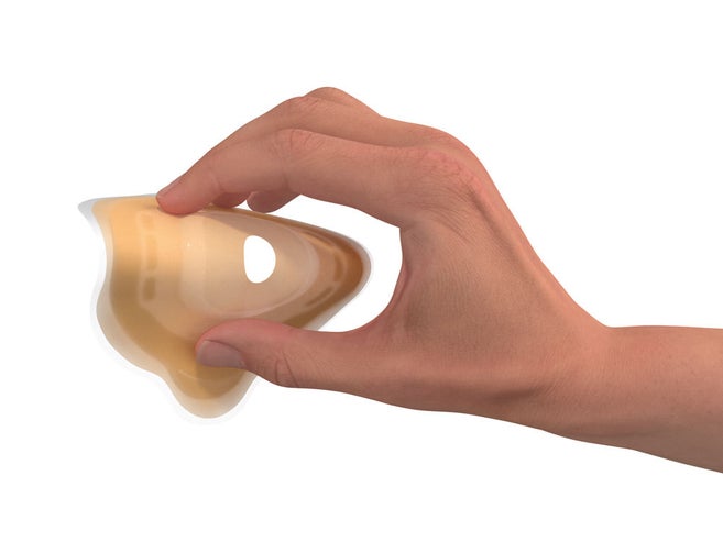 Hand presses the wafer of a soft convex stoma bag to demonstrate its flexibility