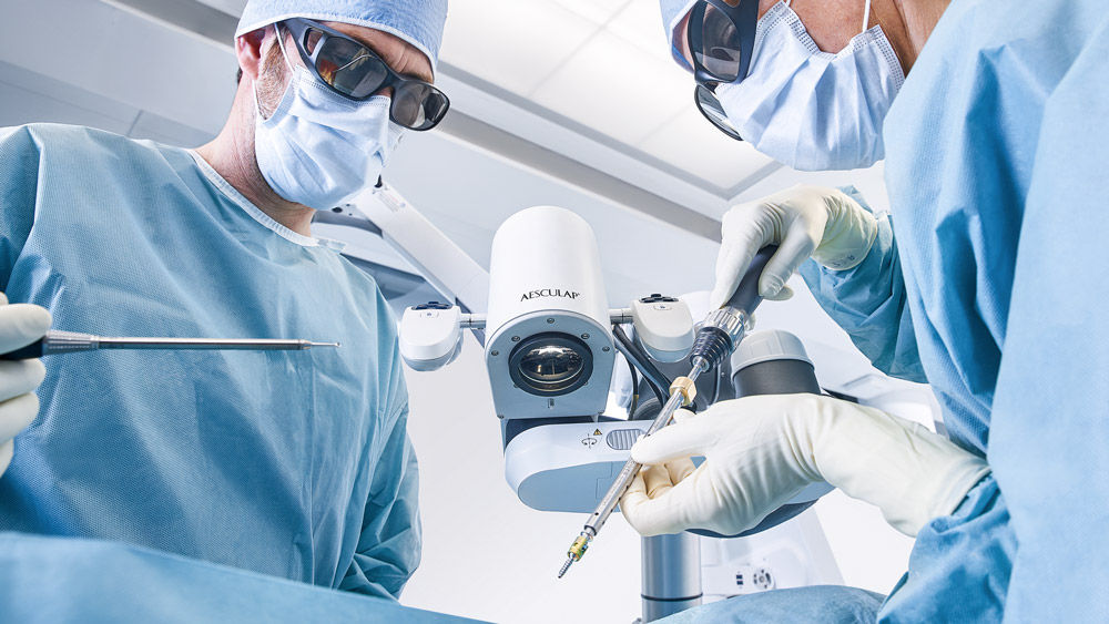 Two surgeons in the OR using a digital microscope during a surgical procedure