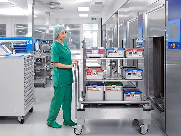 Female CSSD employee with a container trolley