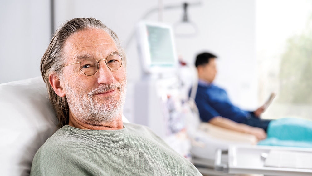 A dialysis patient in a treatment room at a renal care center, smiling and looking comfortable. 