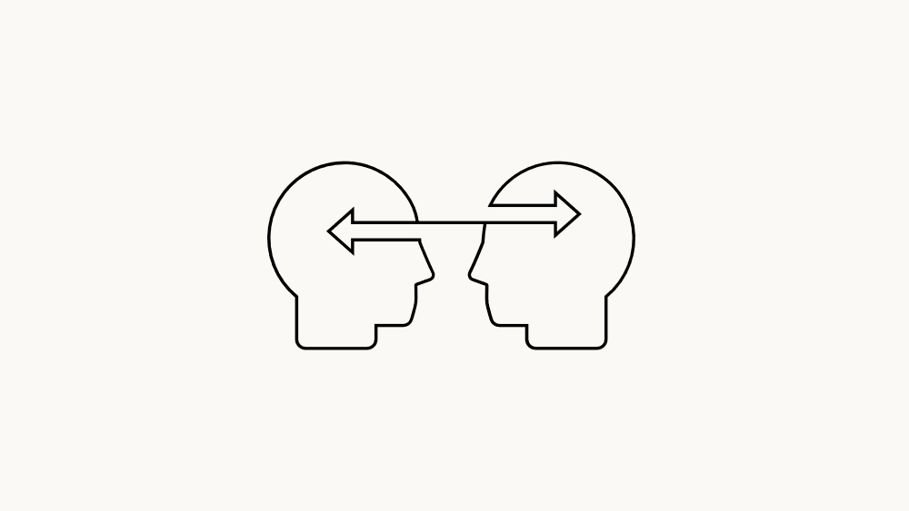 The image features two stylized human heads facing each other with curved arrows pointing back and forth, illustrating the exchange of ideas or collaboration.