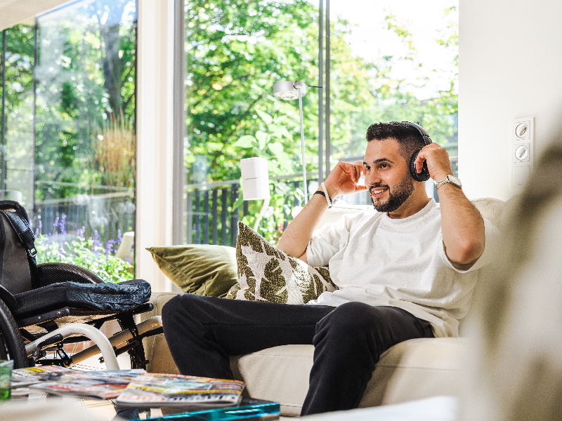 man on a sofa in a private living room with headphones on his head, relaxe 