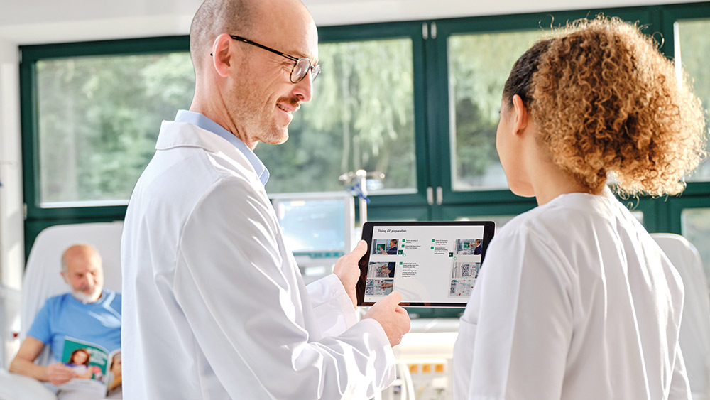 A nephrologist showing an iPad to a dialysis nurse.​