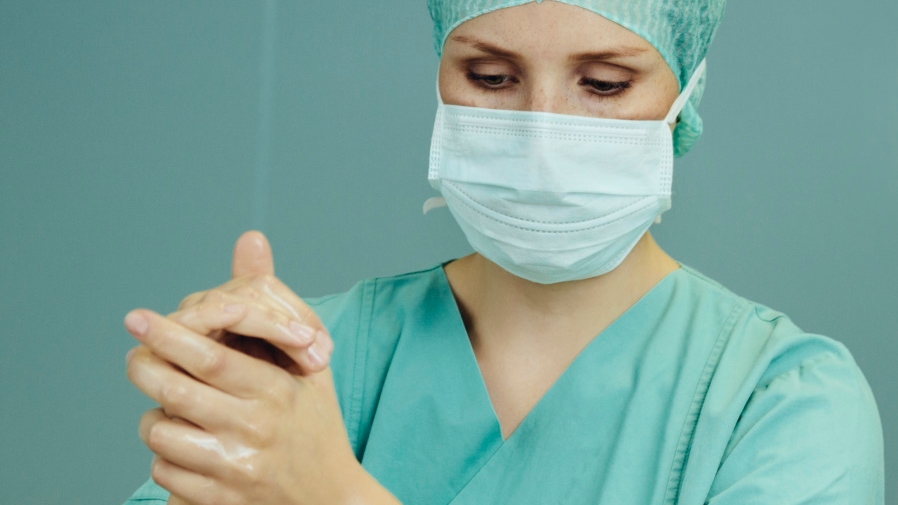 nurse with face mask rubbing hands together