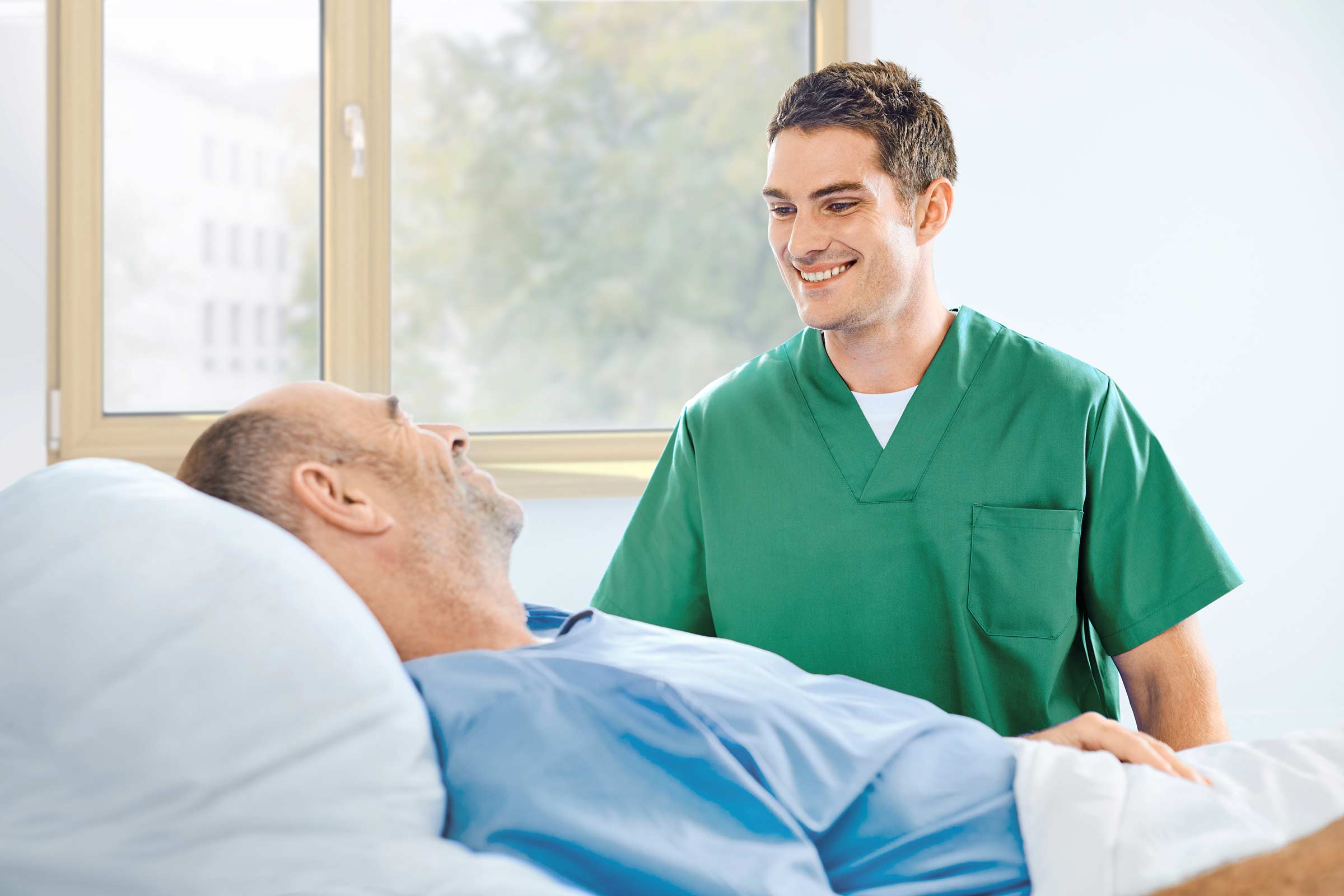 The nurse talks to a patient at the bedside