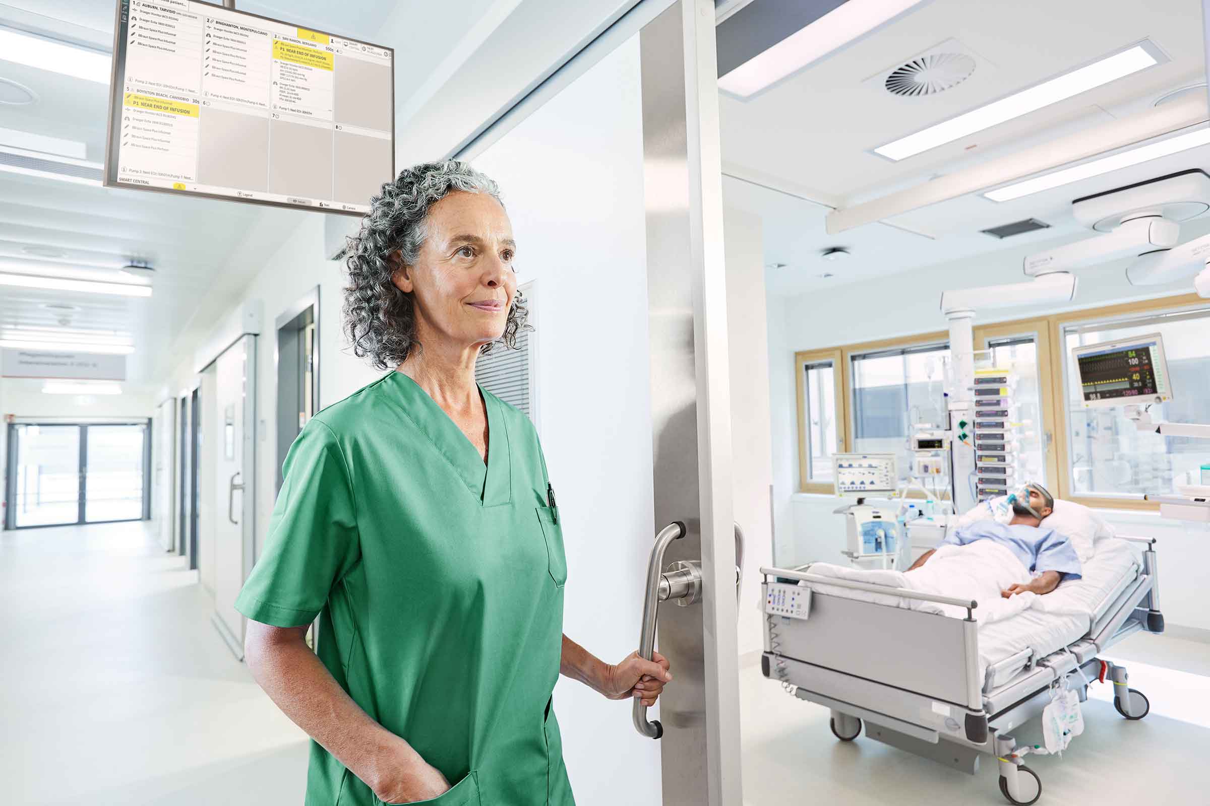 Nurse enters ICU patient room with prioritized alarm handling