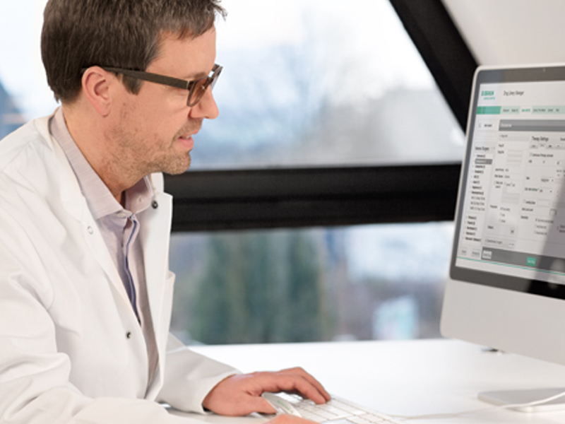 A male healthcare professional is working with a computer in a hospital room; focused on the screen