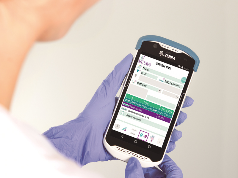 The hand of a medical worker holding a phone with the OncoSafety remote control app open