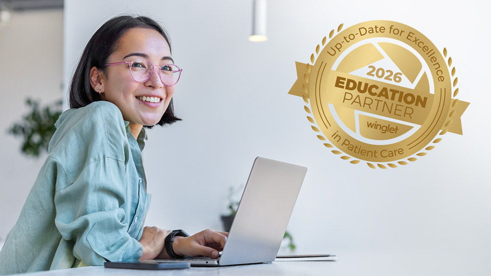 Person working on a laptop at a desk, beside it, a gold badge representing the winglet education partnership