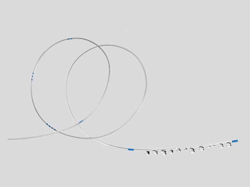Clear flexible thin catheter forming loops featuring measurement markings and small fluid droplets exiting from multiholes located at one end